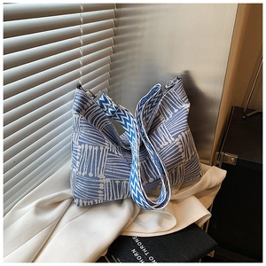 Detail of blue and white geometric jacquard fabric with wide woven shoulder strap on hobo bag