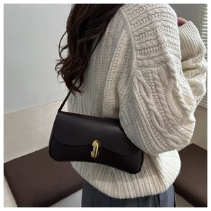 Detail of vintage brown leather underarm bag with gold metal lock on a model outfit