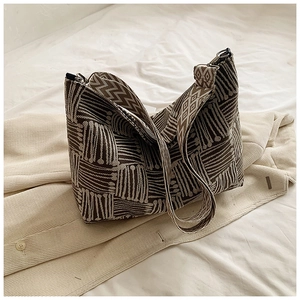 Detail of striped canvas tote bag with textured woven fabric on white linen