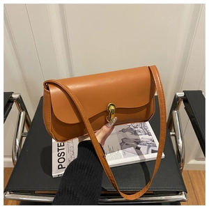 Close-up of caramel leather crossbody bag featuring a distinctive gold J-shaped metal buckle