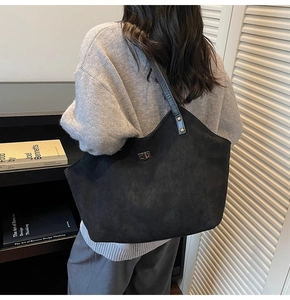 Détail du grand sac cabas en daim noir avec fermoir rotatif argenté et bandoulière large