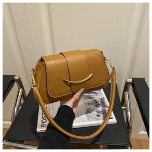 Detail view of brown crocodile texture shoulder bag with gold crescent metal buckle accent