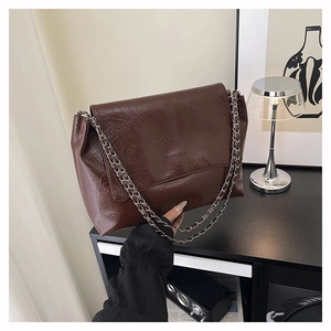 Détail du sac vintage marron foncé avec chaîne et logo FASHION BAGS embossé sur le cuir