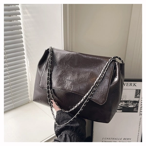 Détail du sac bandoulière en cuir plissé marron foncé avec chaîne argentée et logo
