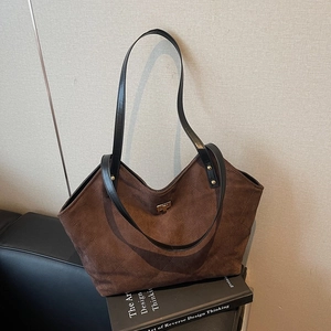 Sac fourre-tout matelassé marron avec fermoir doré et lanières en cuir sur livre