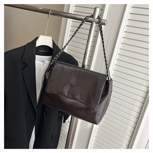Détail de la texture en cuir plissé brillant et bandoulière chaîne sur un sac marron