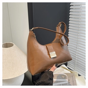 Close-up of caramel brown crescent bag with gold buckle in a vintage indoor setting