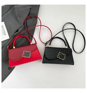 Detail of red and black crocodile embossed crossbody bags with metal ring handles