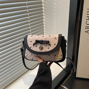 Pink pleated crossbody bag with black bow print and metal heart pendant detail
