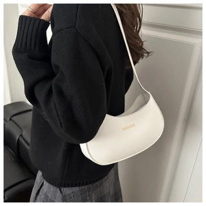 Detail of white half-moon shoulder bag with gold 'FASHION & BAGS' text on leather