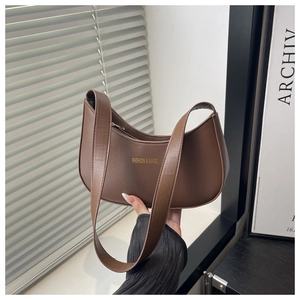 Close-up of a brown leather half-moon hobo bag featuring gold fashion lettering