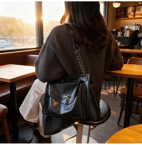 Chic black PU leather tote bag featuring a silver metal bow and stylish chain strap