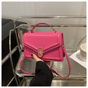 Detail of hot pink crossbody bag showing glossy texture and golden metal twist lock