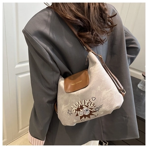 Canvas shoulder bag featuring chic brown leather trim and baseball cartoon character detail