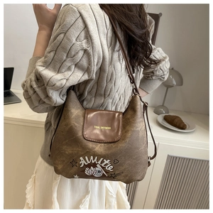 Detail of vintage brown leather tote bag with embroidered cartoon baseball graphic