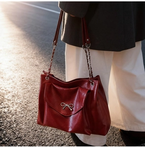 Close-up of deep red tote bag featuring a glossy leather finish and silver bow detail