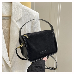 Détail du sac bandoulière noir en daim et cuir avec accents dorés et poignée