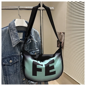Detail view of high-capacity nylon crossbody bag featuring green gradient and FE letter print