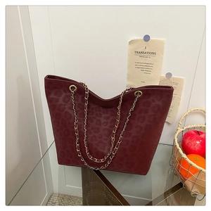 Close-up of leopard print suede tote with golden chain strap and dark red microfiber texture