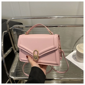 Close-up of pink crossbody bag with gold oval twist lock and smooth leather texture