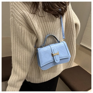 Quilted light blue square handbag with gold buckle shown on a knit sweater outfit