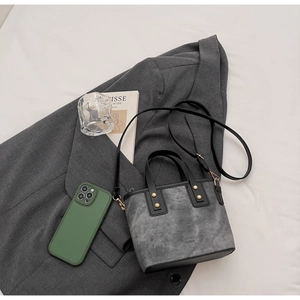 Detail of grey textured tote bag with black leather trim and embossed fashion lettering