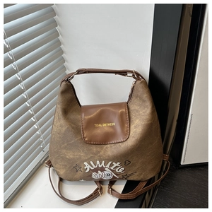 Detail of vintage brown leather tote bag with stylish print on a white windowsill