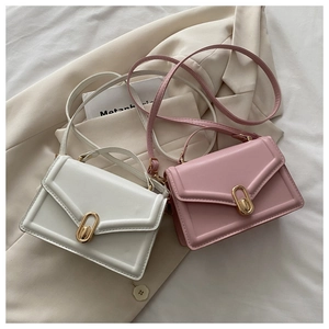 Flat lay of small white and pink crossbody bags with oval gold buckles and top handles