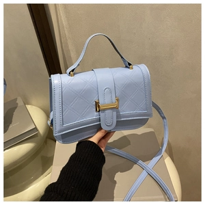 Detail of light blue quilted leather handbag with elegant gold clasp and top handle