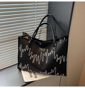 Close-up of black tote bag with heartbeat embroidery and New York fashion leather patch
