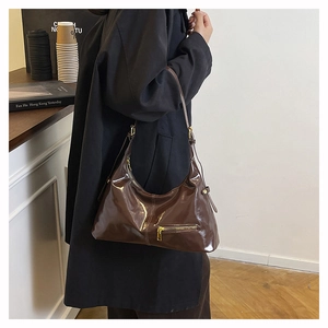 Détail du sac hobo en cuir verni marron foncé avec bandoulière réglable et dorures