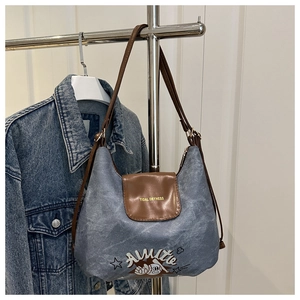 Detail of blue denim hobo bag featuring brown leather flap and retro graphic prints