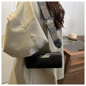 Close-up of black cylinder bag with an ethnic patterned wide shoulder strap and metal zipper