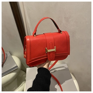 Detail of red quilted leather crossbody bag with elegant gold metal buckle and top handle
