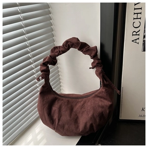 Détail du sac hobo en daim marron foncé avec anse plissée et texture froncée