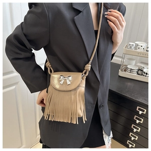 Detailed view of the khaki fringe crossbody bag with silver bow buckle worn by a model