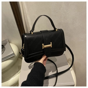 Close-up of black quilted leather handbag with gold clasp and elegant handle