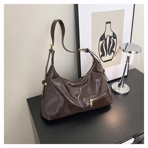 Detaillierte Makroansicht der dunkelbraunen Hobo-Bag mit Glanzfinish und Gold-Hardware