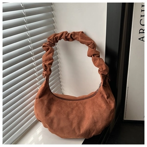Détail de la texture en daim marron et de la poignée plissée du sac hobo rétro