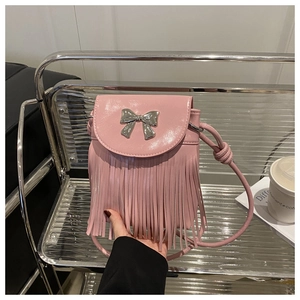 Detailed view of pink crossbody bag featuring a silver bow buckle and long fringe tassels