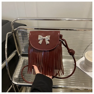 Detail of burgundy tassel bag with silver bow accent on an urban style shelf
