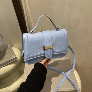 Light blue quilted leather crossbody bag with top handle and gold metal buckle detail