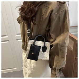 Détail du petit sac tissé avec poignées en cuir noir et pochette à monnaie dorée