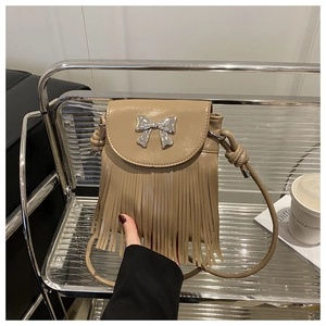 Detail of khaki leather crossbody bag with silver bow hardware and fringe tassel trim