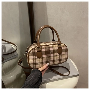 Detailed macro view of the brown plaid wool fabric and leather handle on the Boston bag
