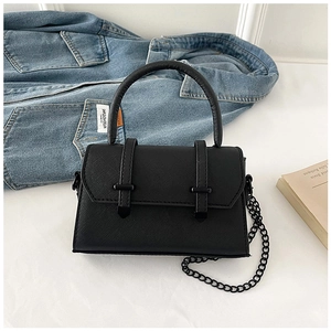 Detail of black Saffiano mini bag with matte chain strap and top handle on denim jacket