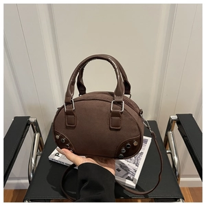 Dettaglio dei rivetti argentati e della texture in camoscio opaco sulla borsa marrone