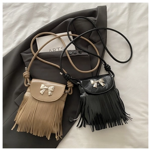 Close-up of tassel charms and metal bow buckle on vintage crossbody bag details