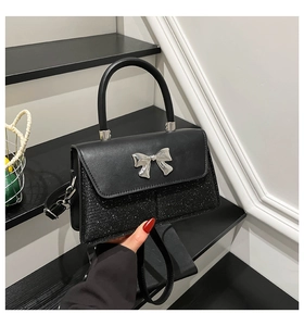 Detailansicht der schwarzen Handtasche mit Silberschleife und glitzernden Pailletten
