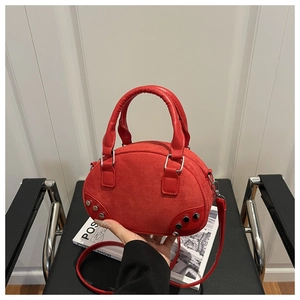 Dettaglio borsa bowling in camoscio rosso con rivetti argentati e finiture in pelle